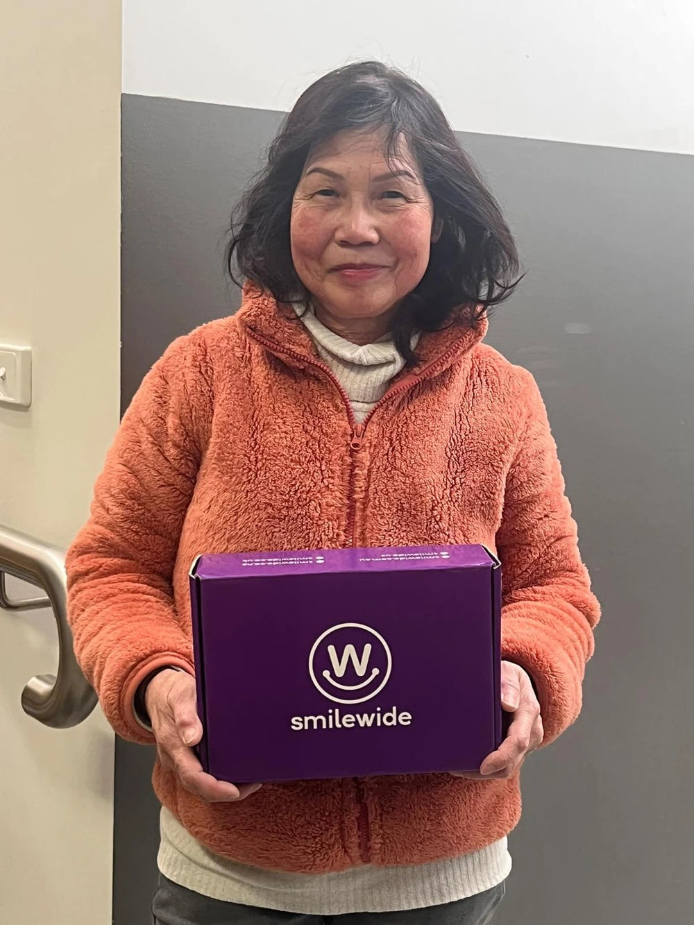SmileWide community member holding a SmileWide package